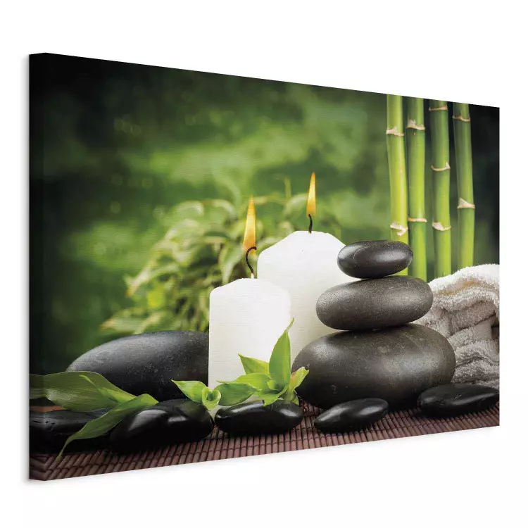 Spa and nature - white candles and stones surrounded by green bamboo