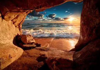 Wall Mural Cave by the beach - landscape with a restless sea at sunset Wallpaper Cropper